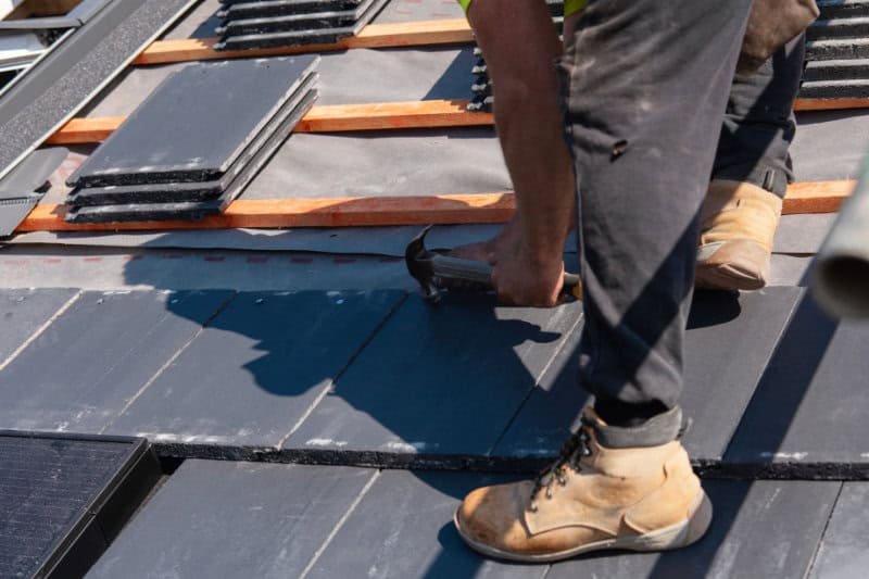 Roofer fitting slate tiles on a roof in Norwich